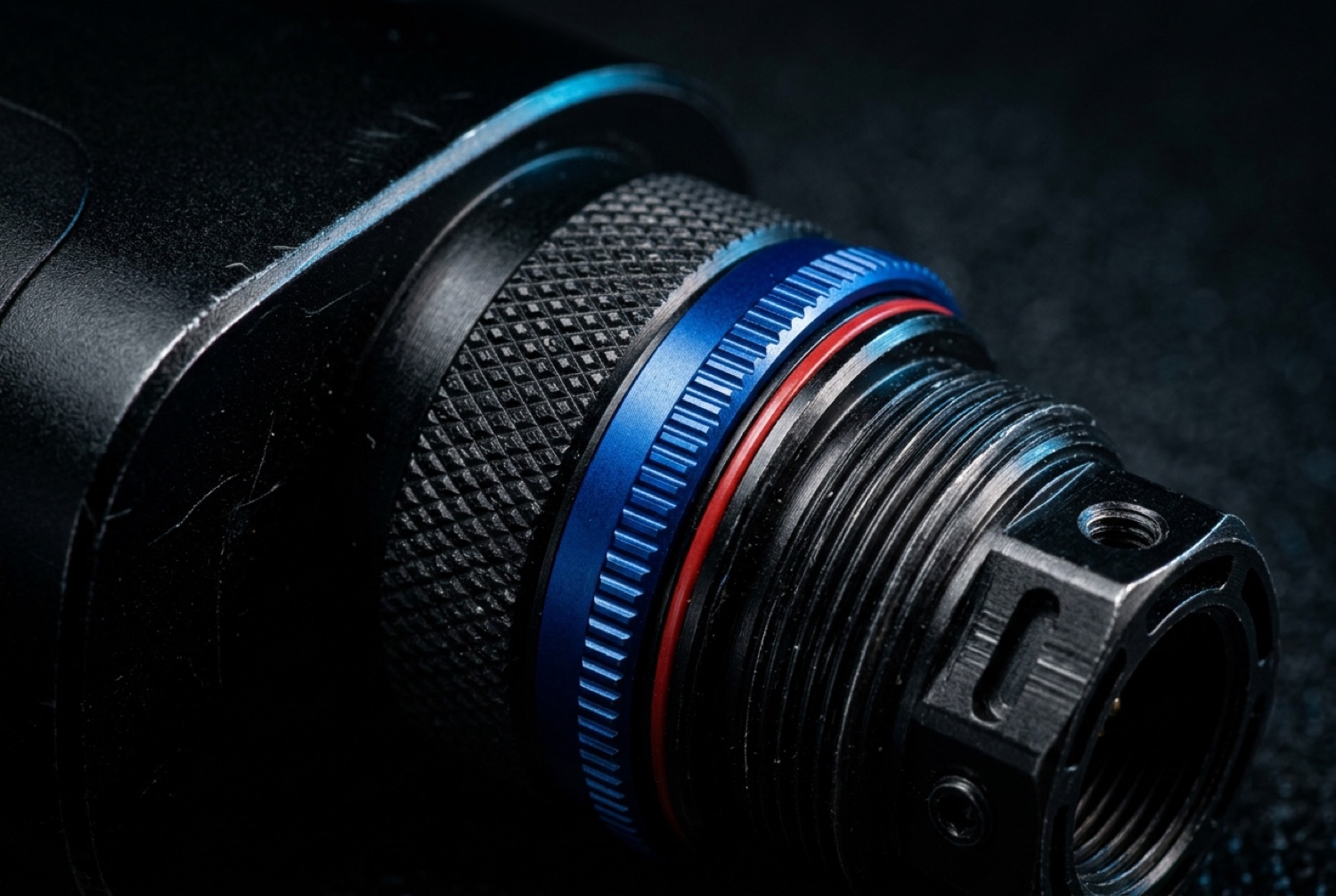 Macro detail of a machined aluminum transmitter connector with blue and red anodized rings